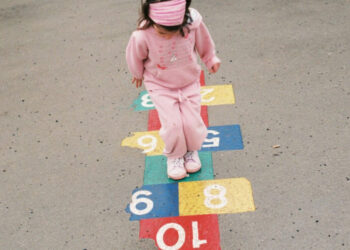 Little girl playing hopscotch outside